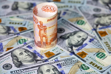 Fototapeta premium Russian rubles on background of US dollars. Concept of exchange rate, sanctions, falling ruble