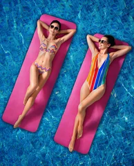 Fotobehang Beautiful young women floating on pink mattress in swimming pool © konradbak