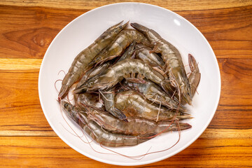 Fresh shrimp or prawn on white plate, Raw prawns  on woodend background, Fresh Seafood ready to cook.