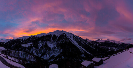 Winter scenery while sunrise in the European Alps, Graubuenden, Switzerland, with snow-covered mountains, clouds, and sky