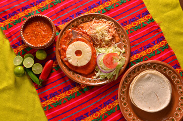 A closeup shot of traditional food with meat and vegetables served on a clay plate with tortillas
