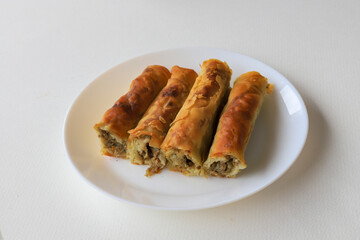 pie with ground beef filling, rolls of puff pastry with meat on plate