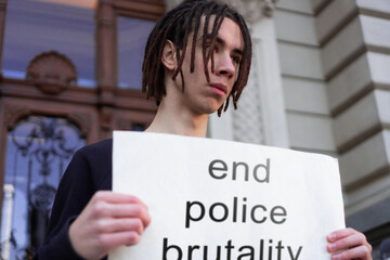 A male student is protesting against police brutality in front of courthouse.