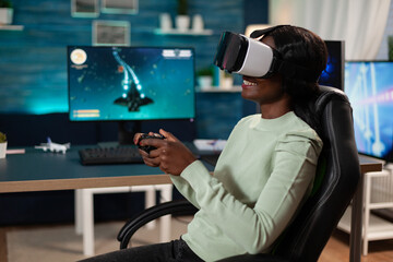 Pro gamer woman wearing virtual reality googles holding gaming controller playing space shooter videogames during online competition. Concentrated gamer playing games using RBG computer equipment