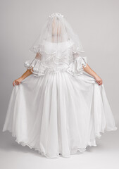 Obraz premium the bride stands with her back in a veil and demonstrates a wedding dress on a white background in full growth