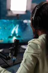 Successful gamer woman with gaming headset while playing online videogame during space shooter championship. Pro player talking into microphone with players on streaming live using RGB computer © DC Studio