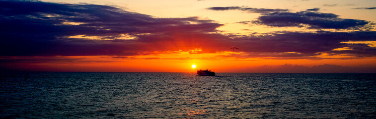 Fototapeta na wymiar Kreuzfahrtschiff fährt in den Sonnenuntergang