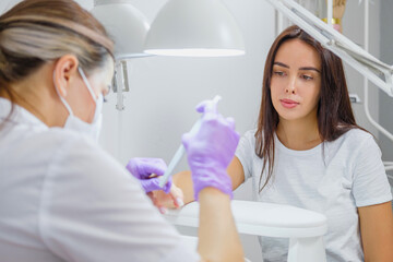 Fototapeta premium Closeup shot of woman in nail salon receiving manicure by beautician with nail file and machine. Woman getting nail manicure.