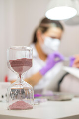 Closeup shot of woman in nail salon receiving manicure by beautician with nail file and machine. Woman getting nail manicure.