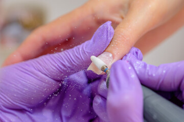 Closeup shot of woman in nail salon receiving manicure by beautician with nail file and machine....