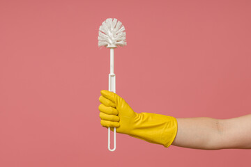 a hand in a rubber glove holds a toilet brush on a colored background