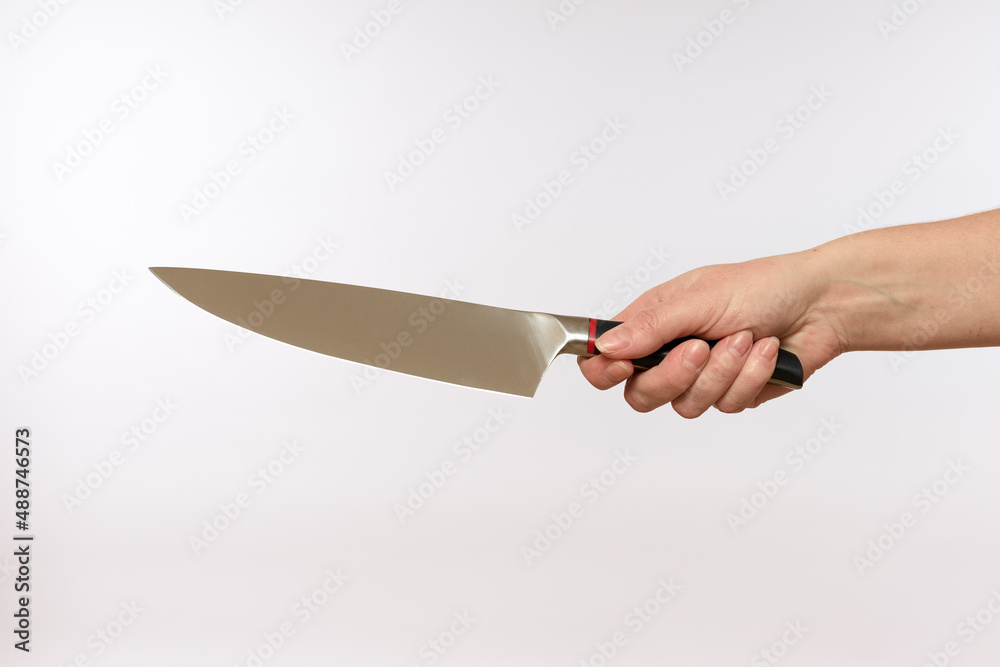 Wall mural female hand holding a sharp steel knife on a white background, close-up