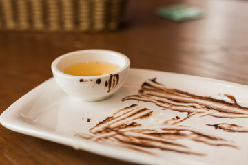 Close up of dirty spoon after eating chocolate cake on white plate in cafe