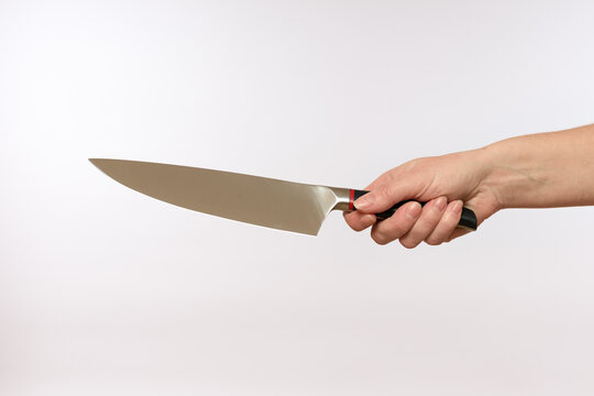 female hand holding a sharp steel knife on a white background, close-up