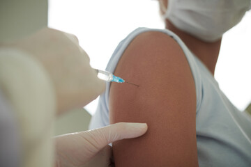 Close-up of teenager getting injection from covid in her arm at hospital