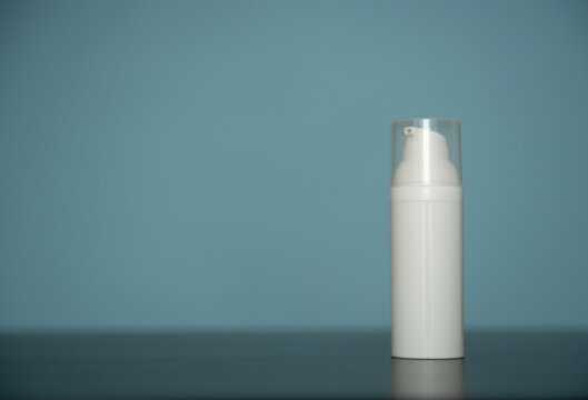 Flacon de crème pour visage en plastique blanc sur fond bleu - mockup pour produit cosmétique