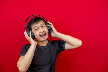 An Asian man is having fun and dancing while listening to a song using a headset.