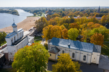 Fototapeta na wymiar Panoramic aerial view of the Kremlin in Veliky Novgorod, golden autumn in the city, yellow treetops, a bridge over the Volkhov river, city sandy beach, a fortress.Sophia Cathedral.