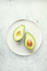 Avocado on white plate. Top view. Banner. Pop art design, creative summer food concept. Green avocadoes, minimal flat lay style.