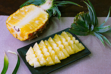Pineapple slices and pineapple shelled Asian-style on the wooden background.