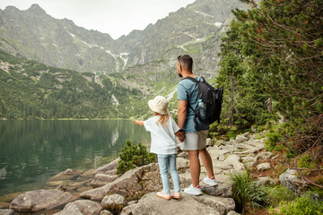 Man and child tourists in mountains at Morskie Oko lake near Zakopane, Tatra Mountains, Poland. Family travel concept. - obrazy, fototapety, plakaty
