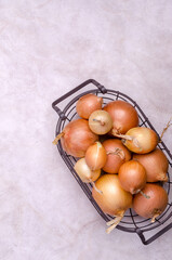 Fresh yellow onions in a metal basket