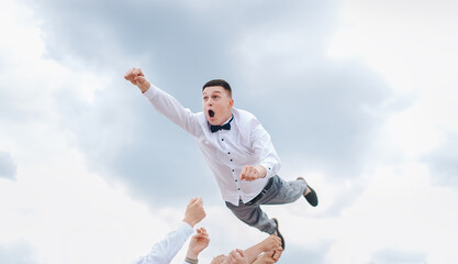 Fototapeta na wymiar Friends throw the groom, the man into the sky at the wedding. Photography, concept.