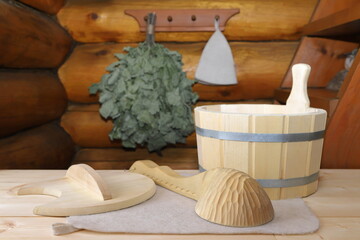 On a wooden desk are traditional sauna accessories on the background a log wall with hanging on it...