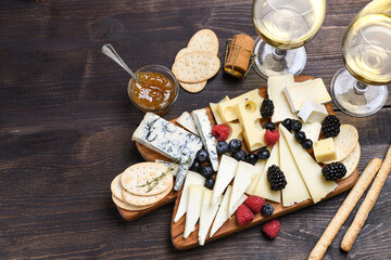 Various types of cheese on a wooden board. Сheese plate  with gorgonzola parmesan brie or camembert and maasdam. served with berries and  crackers 