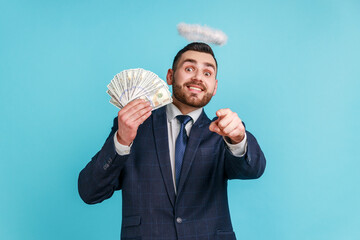 Man wearing official style suit with halo over head pointing at camera, showing fan of dollar bills...