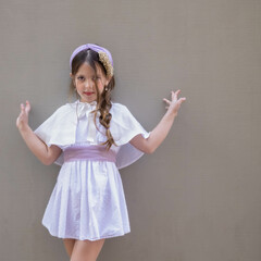 Little Caucasian girl, schooler, dancing in her white and violet ceremony dress and cape, looking so confident and elegant.