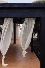 White curtains of outdoor terrace on a windy summer day. Outdoor home or house decor for warm seasons.