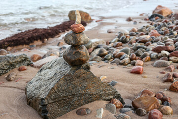 Rock balancing stone stacking near beautiful baltic sea on shore sand.