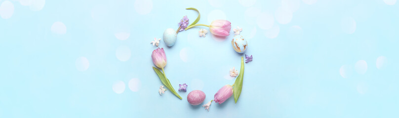 Beautiful frame made of painted Easter eggs and beautiful flowers on blue background with space for text