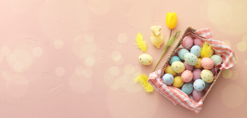 Basket with painted Easter eggs, bunny and tulip flower on color background with space for text