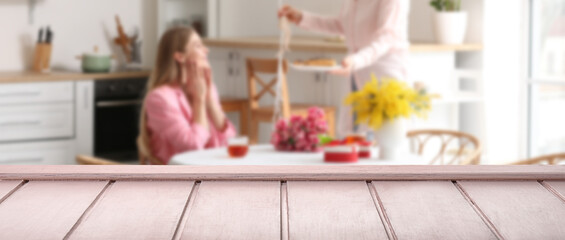 Empty wooden surface and blurred family in kitchen on Easter eve