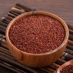 Organic red quinoa in a bowl on wooden table background.