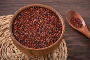 Organic red quinoa in a bowl on wooden table background.