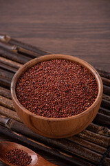 Organic red quinoa in a bowl on wooden table background.