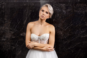 Obraz premium portrait of a beautiful young woman with makeup in a wedding dress on a black background 