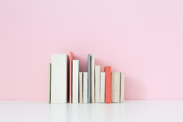 Books on a shelf near pink wall