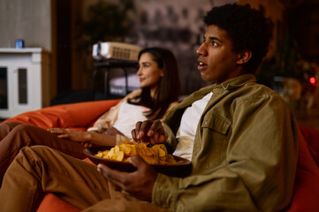 Emotional young couple watching movie at home