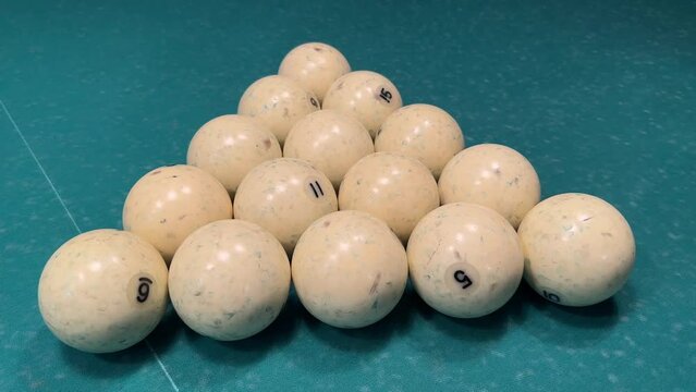 Billiard balls are laid out in the shape of a triangle on a green table of Russian billiards. Ivory balls