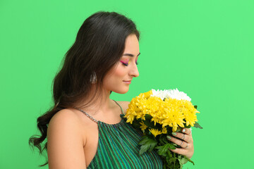Woman with creative makeup holding bouquet of flowers on green background. International Women's Day