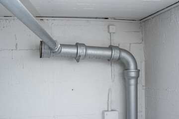 Thick plastic plumbing twisting tubes  inside communal laundry room inside apartment building. No people.
