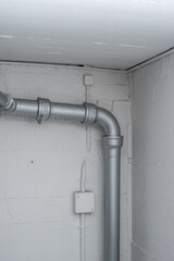 Thick plastic plumbing twisting tubes  inside communal laundry room inside apartment building. No people.