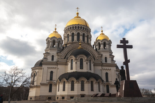 Orthodox church with golden domes and crosses against a clear blue sky with clouds.l