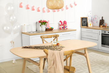 Dining table with Easter cakes, candle and willow branches in kitchen