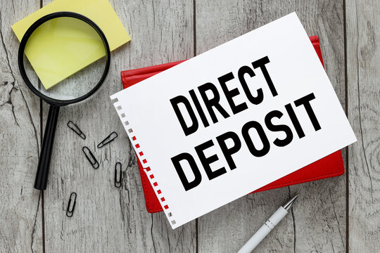 direct deposit. text on a white sheet of paper on a red notepad on the desk