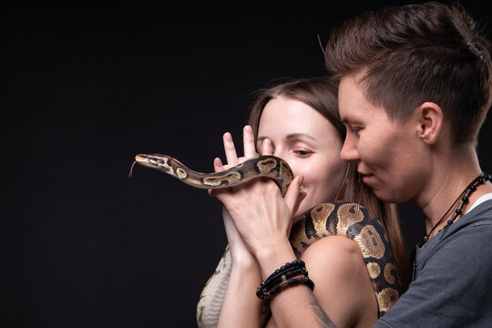 Image of two women with python on black background